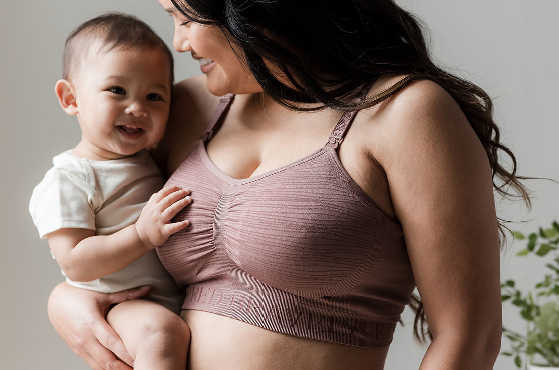 Model wearing the Sublime® Hands-Free Pumping & Nursing Bra in Twilight,  and holding baby