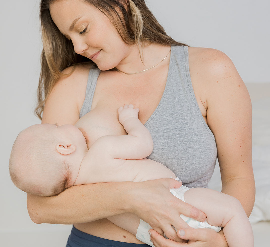 Model wearing the French Terry Racerback Nursing & Sleep Bra in Grey Heather, nursing baby