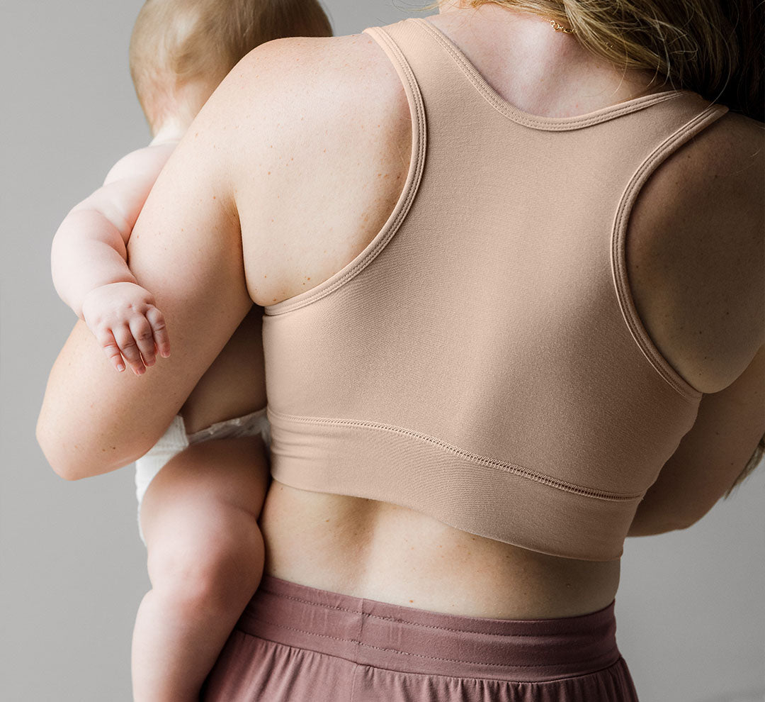 Back view of the French Terry Racerback Nursing & Sleep Bra in Beige on model holding baby