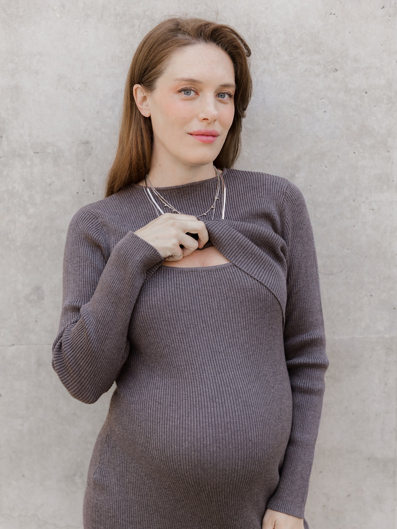 Front view of model outside wearing the 2-in-1 Maternity & Nursing Midi Dress, lifting outer long-sleeve cropped top layer