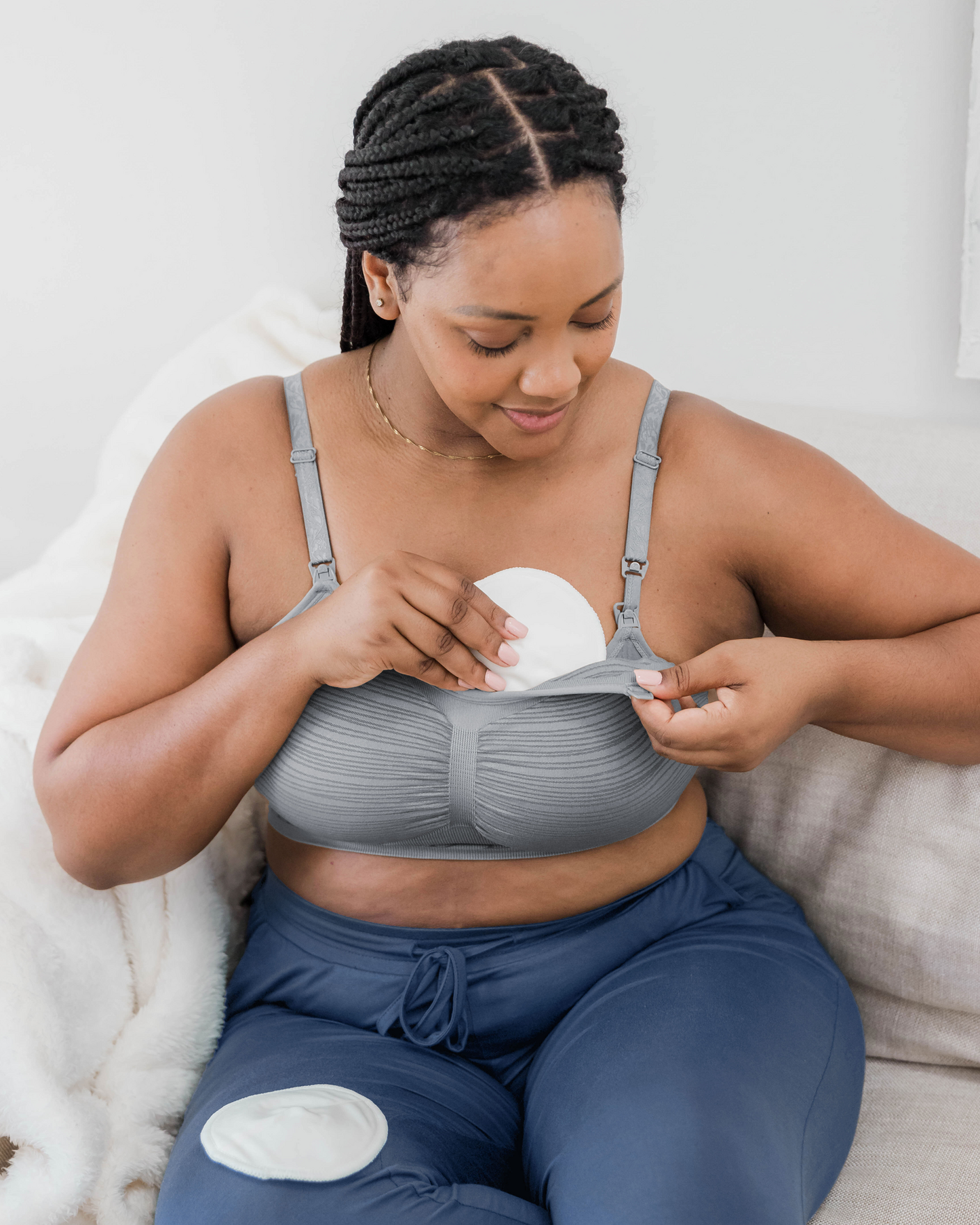 Model wearing the Sublime® Hands-Free Pumping & Nursing Bra in grey, showing how to inset an Organic Bamboo Reusable Nursing Pad