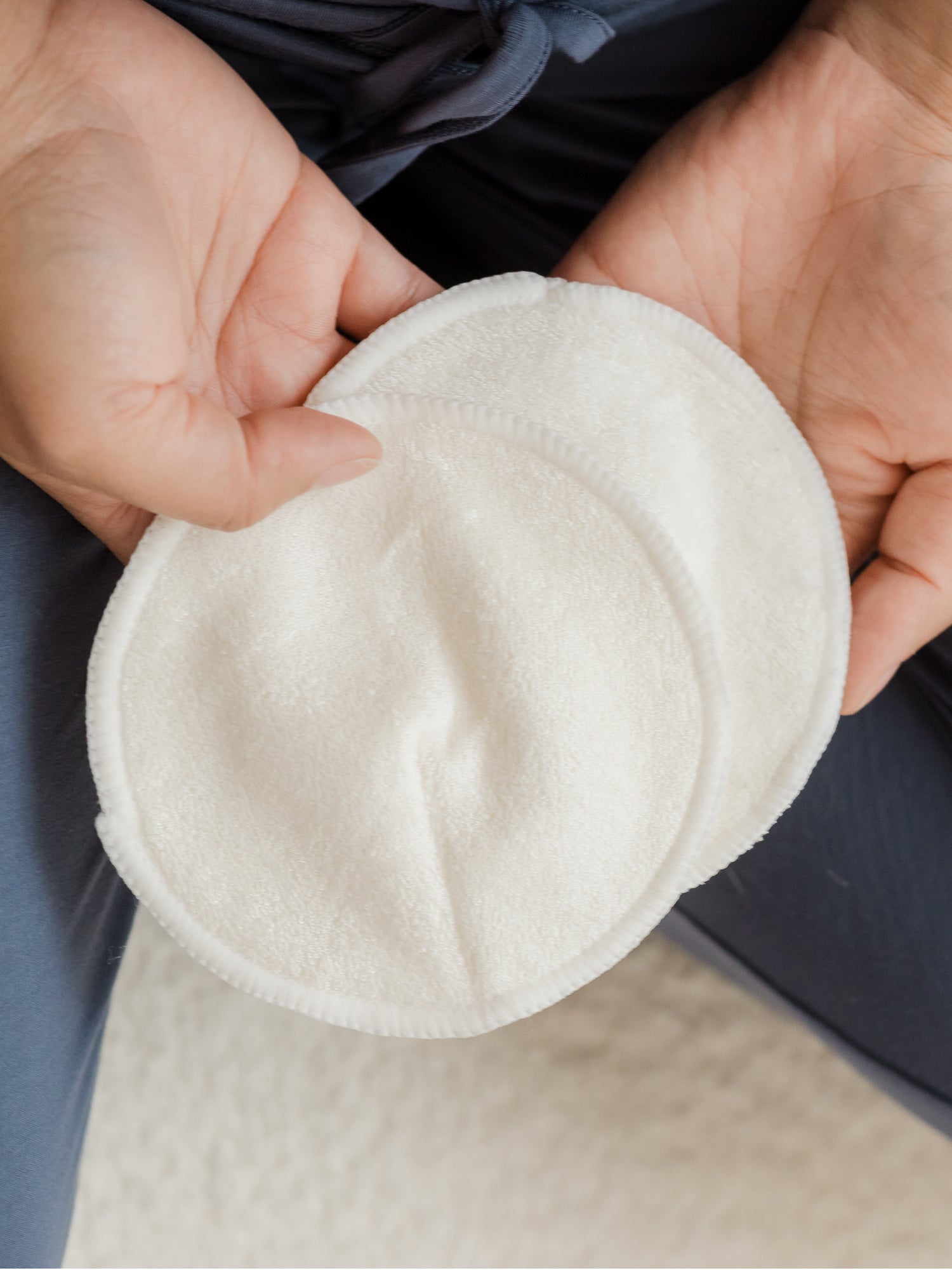 Close up of two Organic Bamboo Nursing Pads held in hands