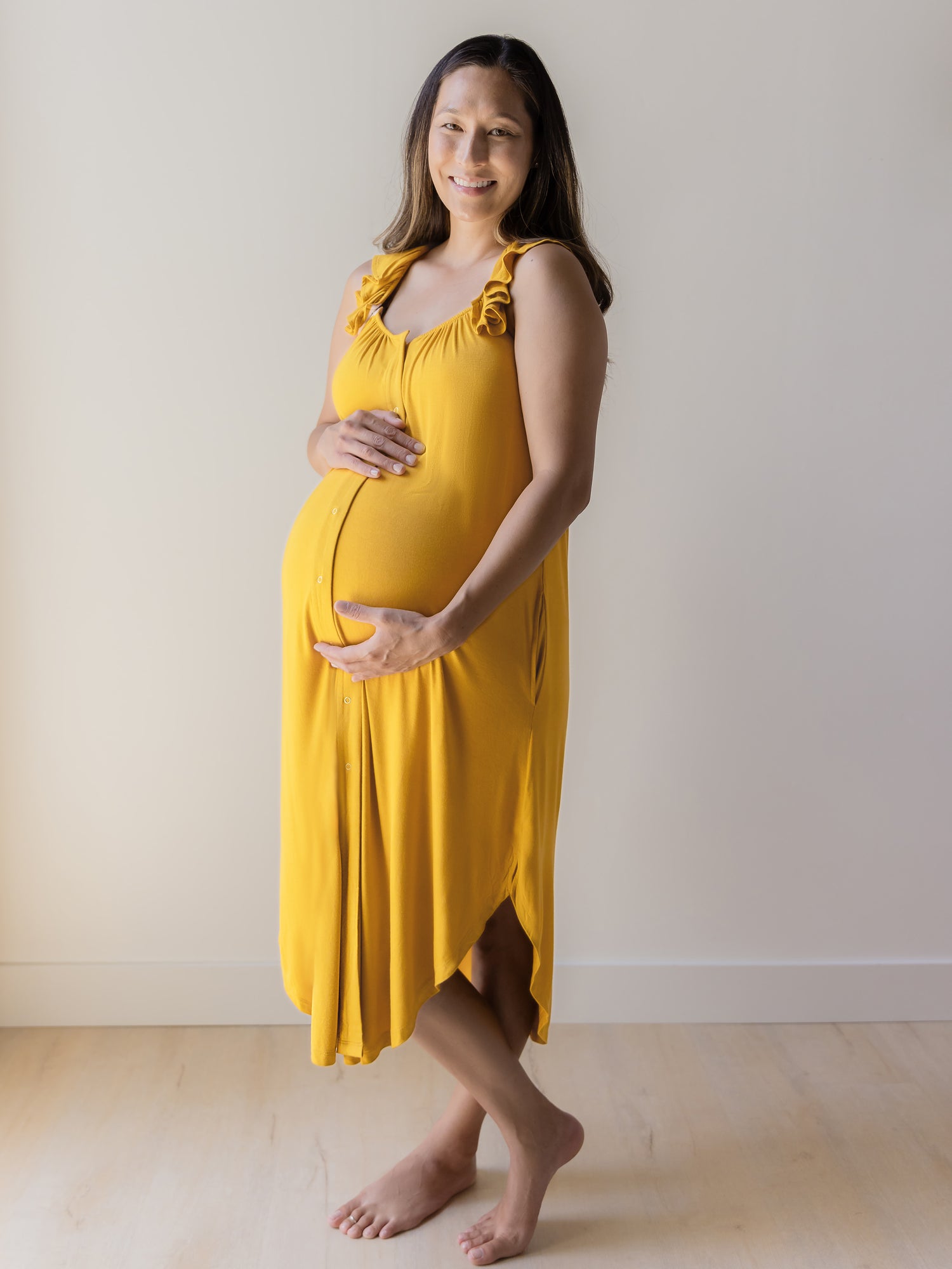 Side view of pregnant model wearing the Ruffle Strap Labor & Delivery Gown in Honey. 