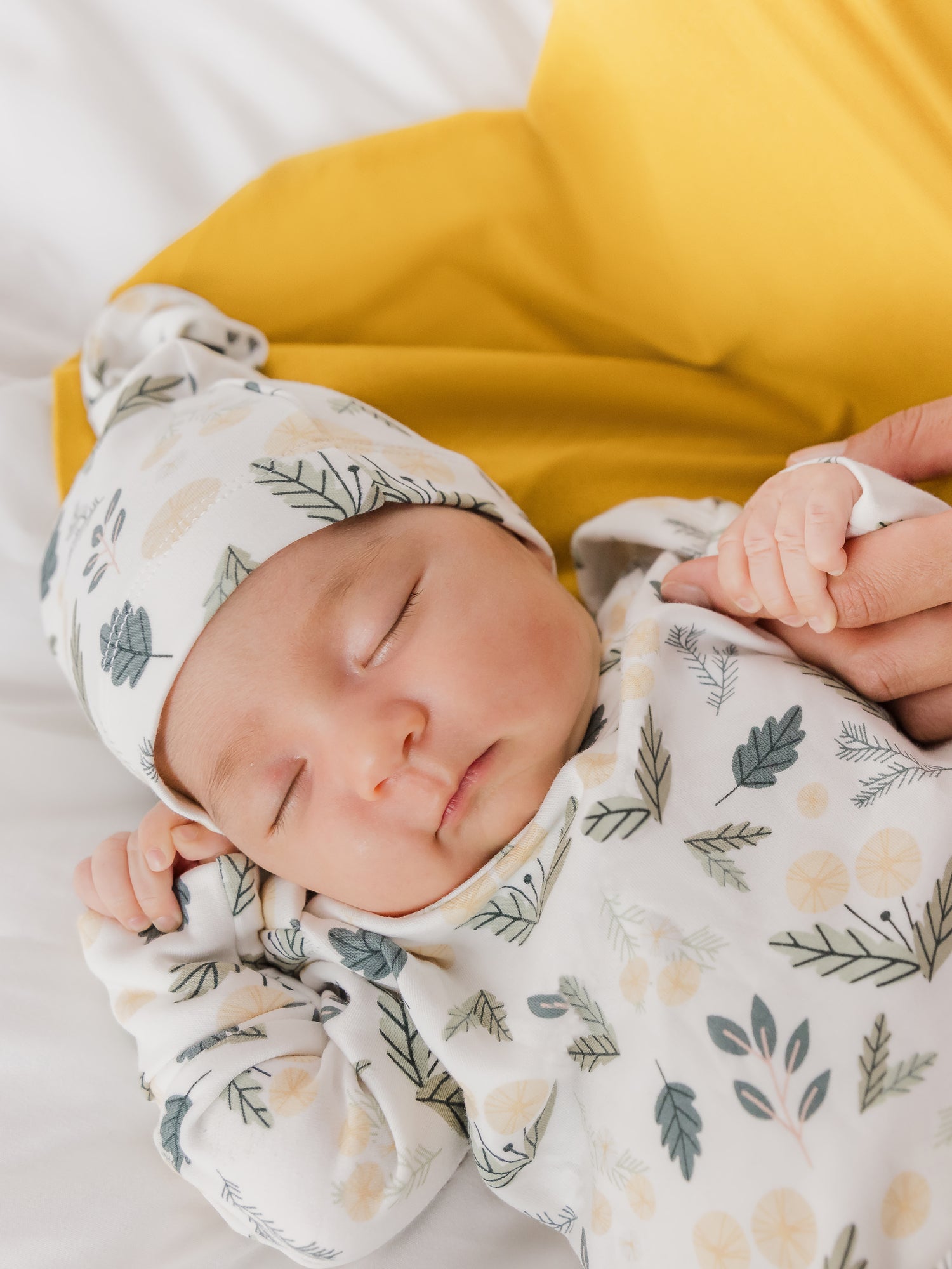 Close up of newborn wearing the Baby Knotted Gown & Hat Set in Honey Dandelion.