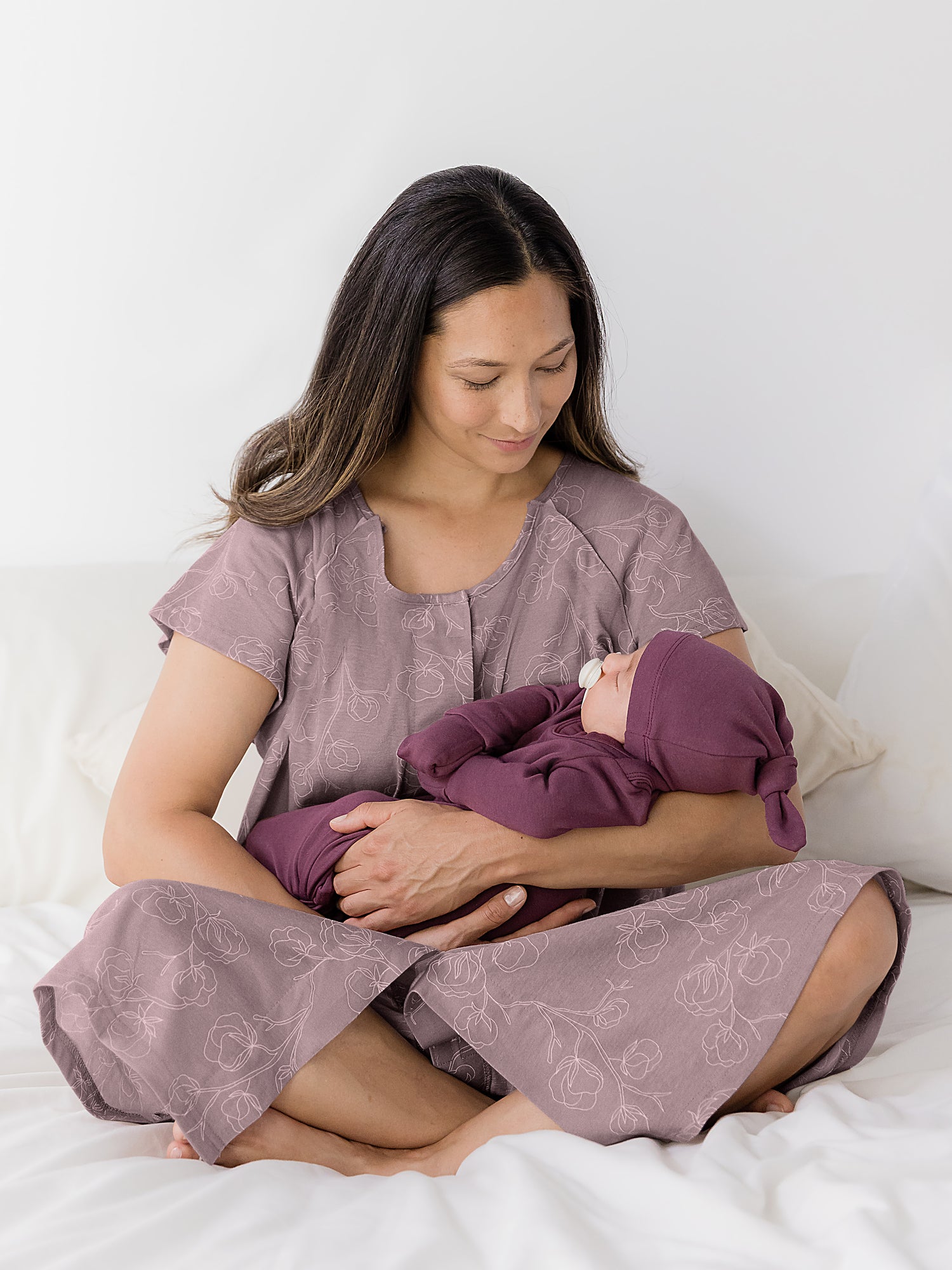 Baby wearing the Baby Knotted Gown & Hat Set in Burgundy Plum being cradled by mom.