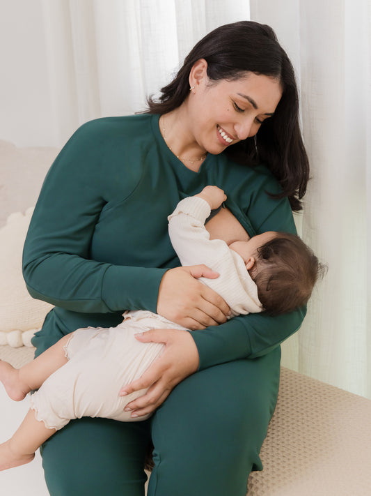 Model sitting and nursing baby, wearing the Bamboo Maternity & Nursing Crew Neck Sweatshirt in Evergreen @model_info:Connie is wearing an X-Large.