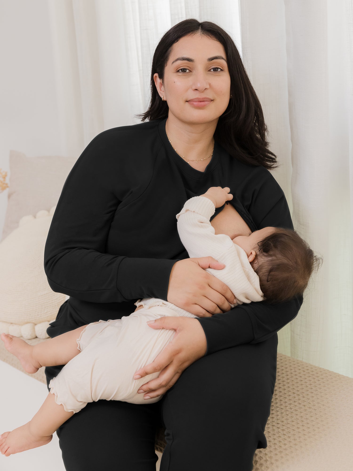 Model sitting and nursing baby, wearing the Bamboo Maternity & Nursing Crew Neck Sweatshirt in Black @model_info:Connie is wearing an X-Large.