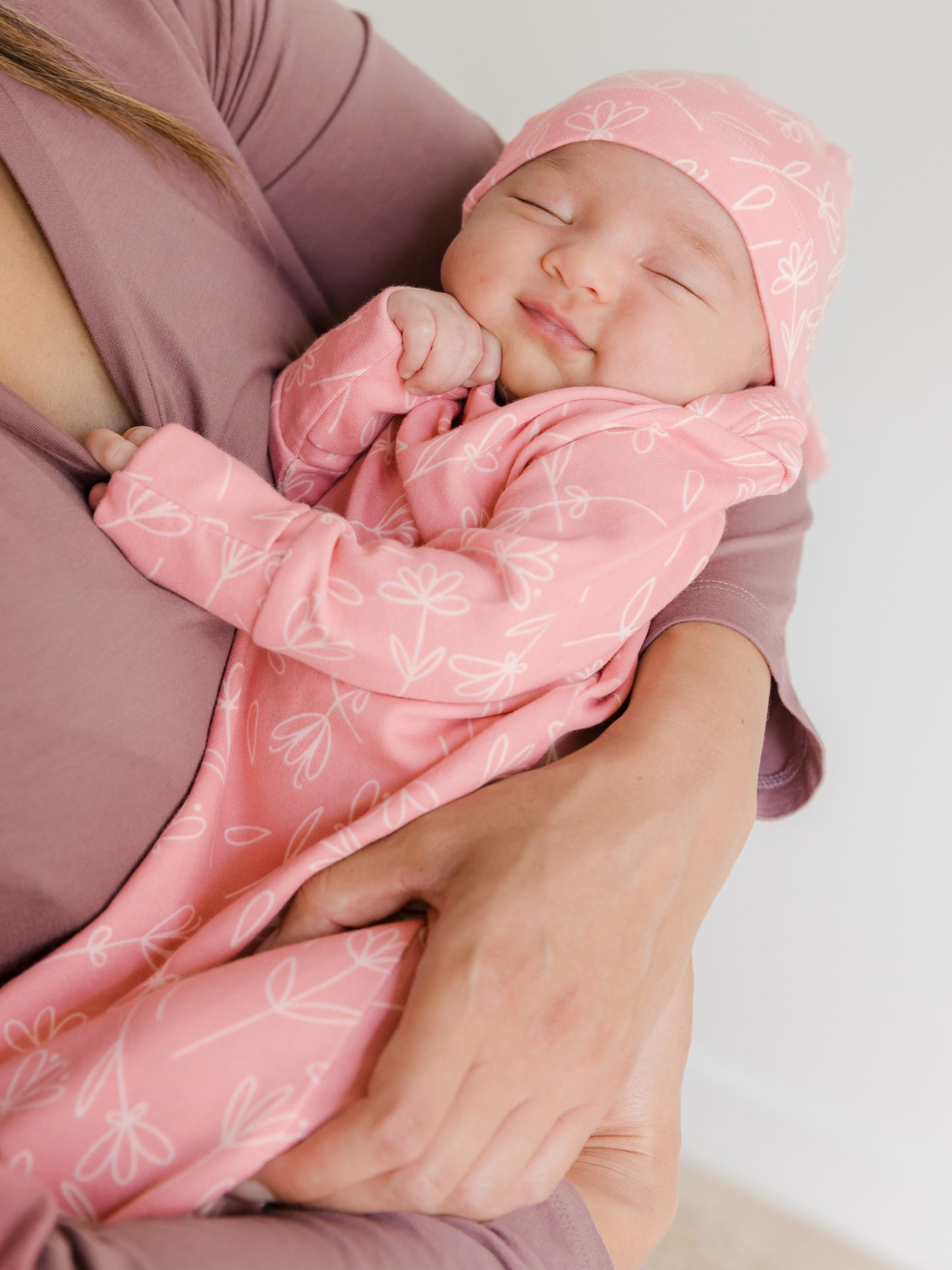 Newborn wearing the Baby Knotted Gown & Hat Set in Pink Floral being cradled by mom.