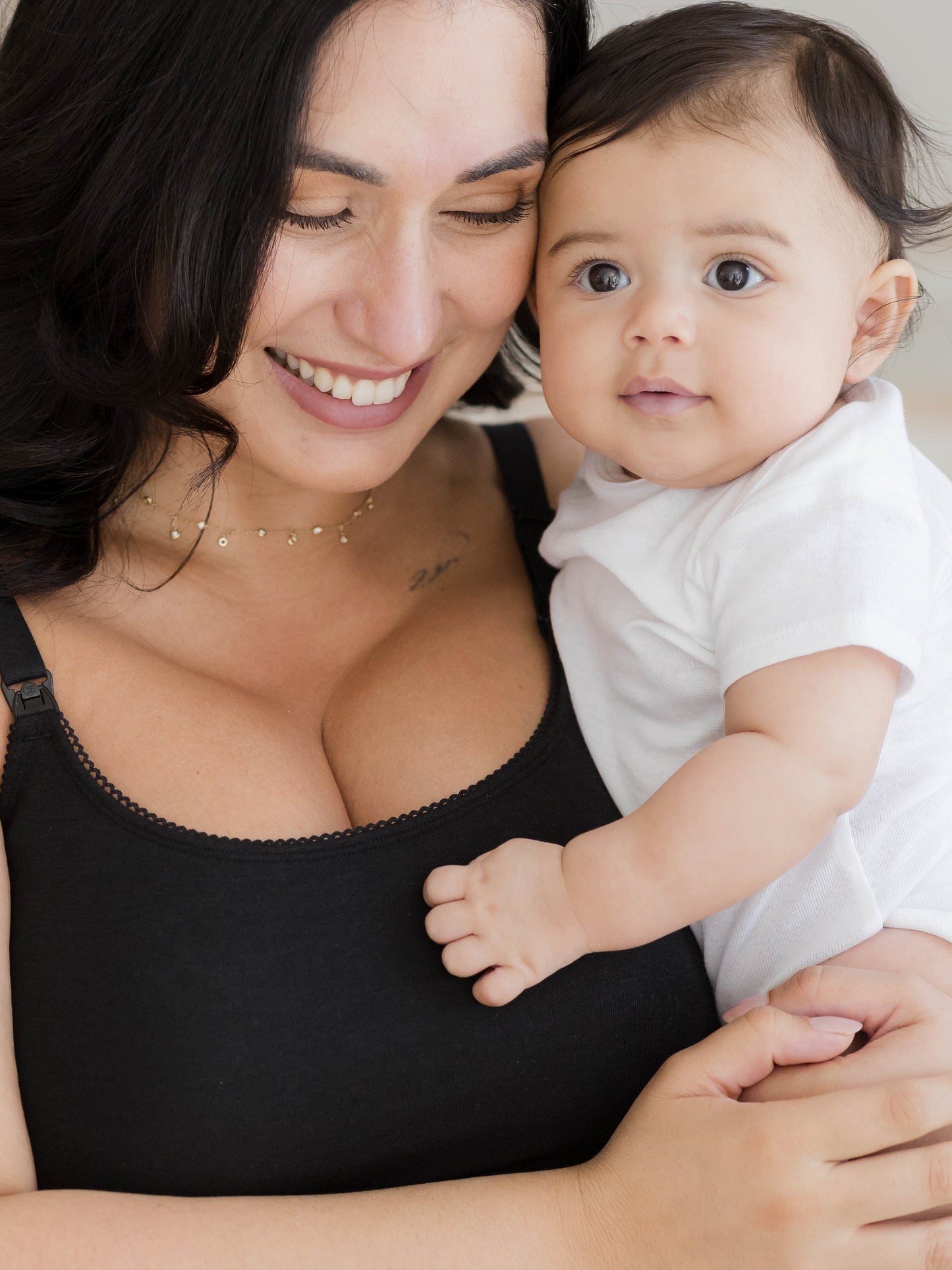Close up image of model holding baby and wearing the Picot Trim Nursing Camisole in black, highlighting the trim detail