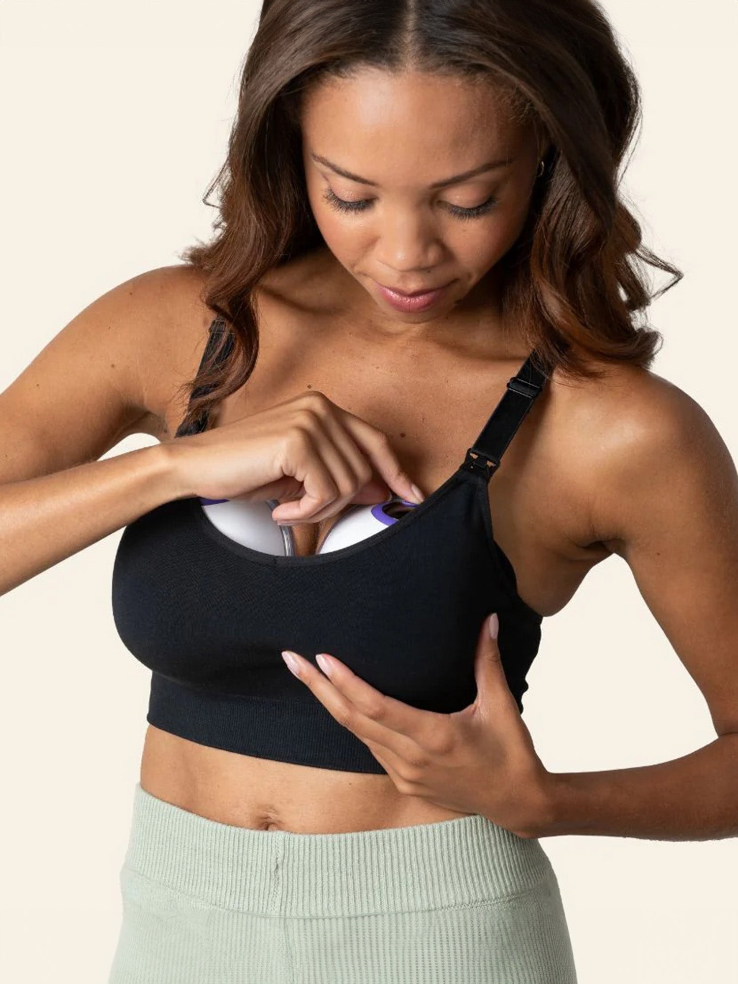 Model using the DiscreetDuo™ Wearable Pump plus Kindred Bravely + Lansinoh Wearable Pumping Bra Bundle, placing pump into bra