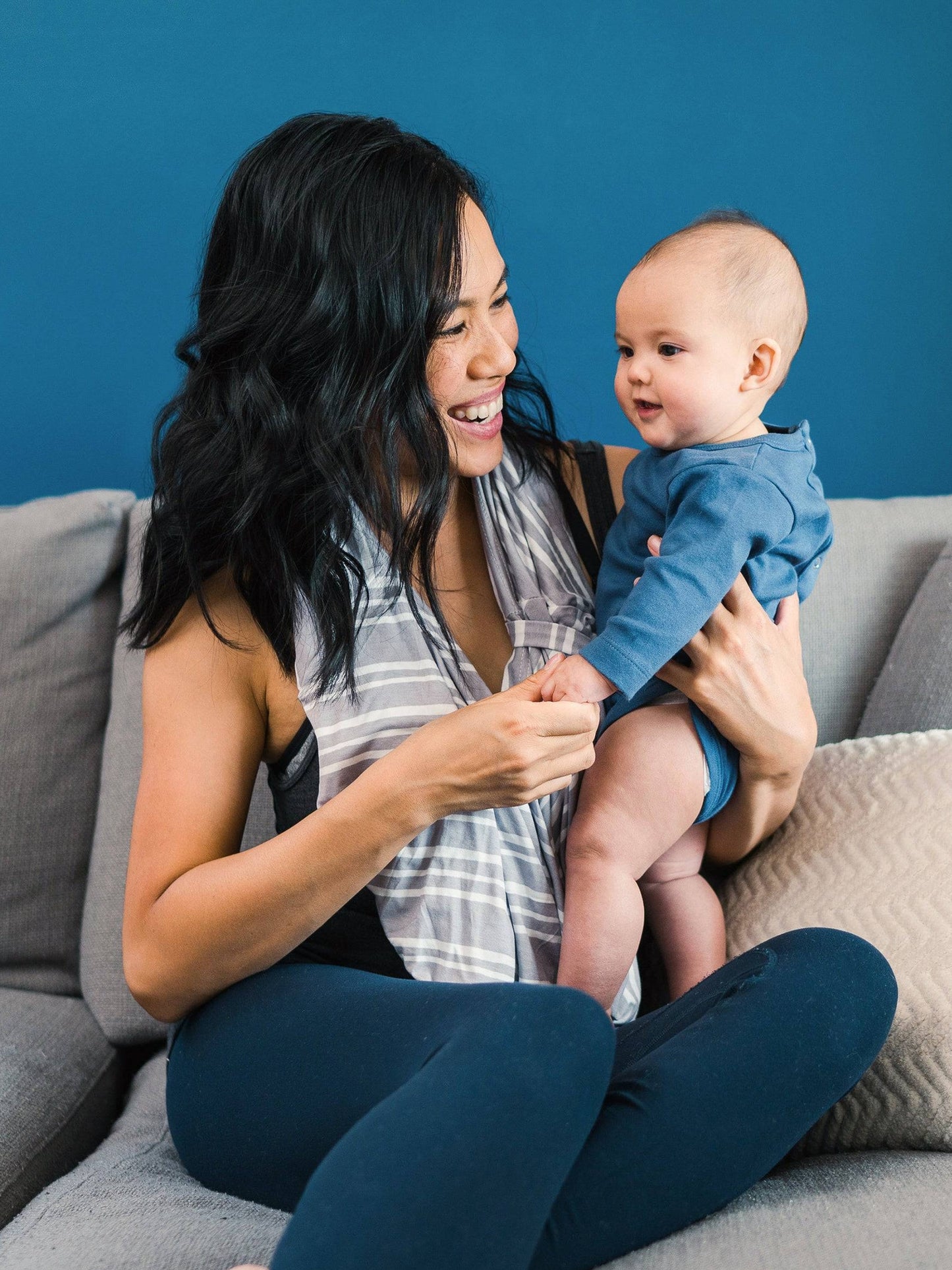 Model wearing the Bebe au Lait - 5-in-1 Multi-Use Nursing Cover in Metro as an infinity scarf, holding baby