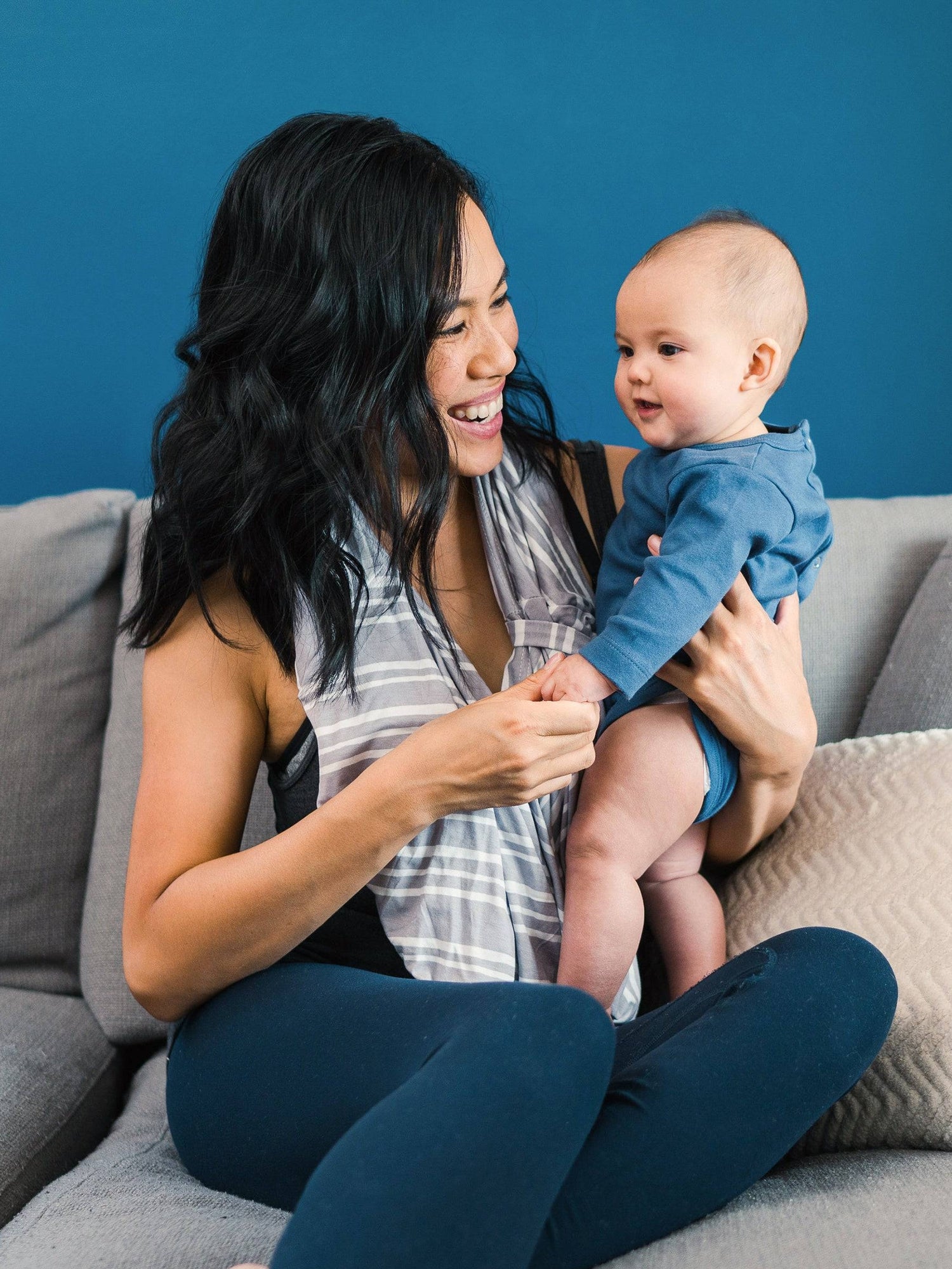 Model wearing the Bebe au Lait - 5-in-1 Multi-Use Nursing Cover in Metro as an infinity scarf, holding baby