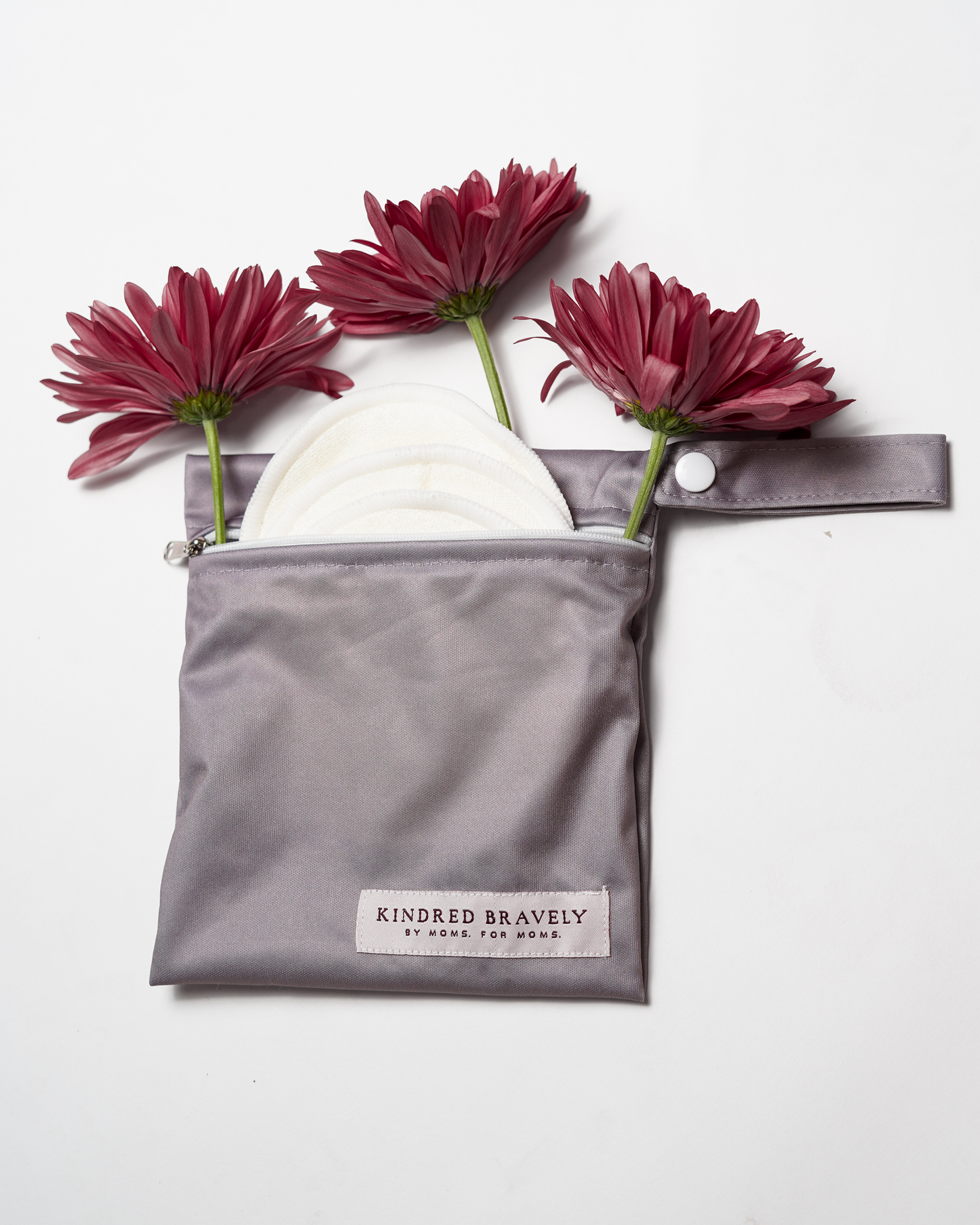 Flat lay of the Organic Bamboo Reusable Nursing Pads against a white background with flowers. 