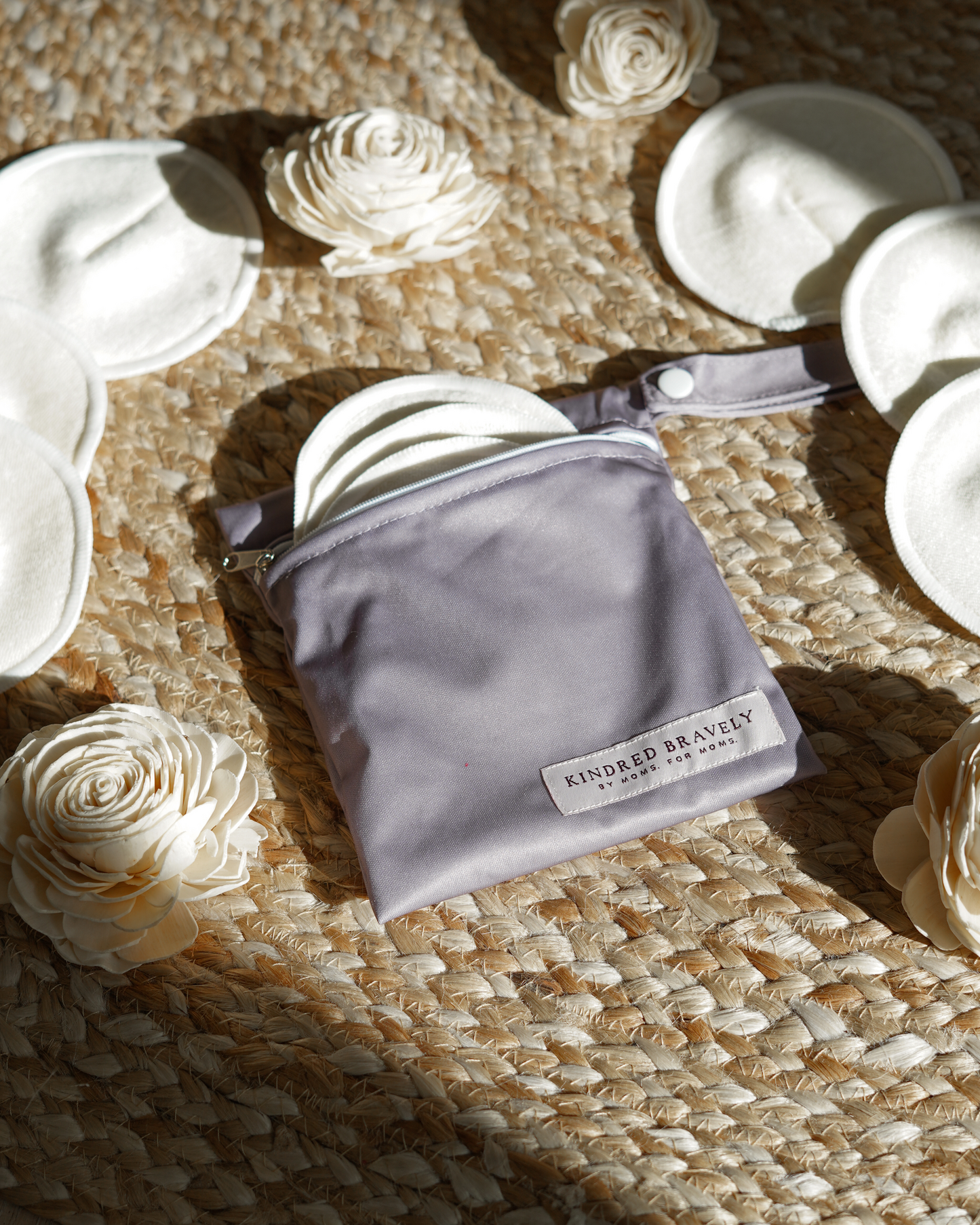 Flat lay of the Organic Bamboo Reusable Nursing Pads against a jute background with flowers. 