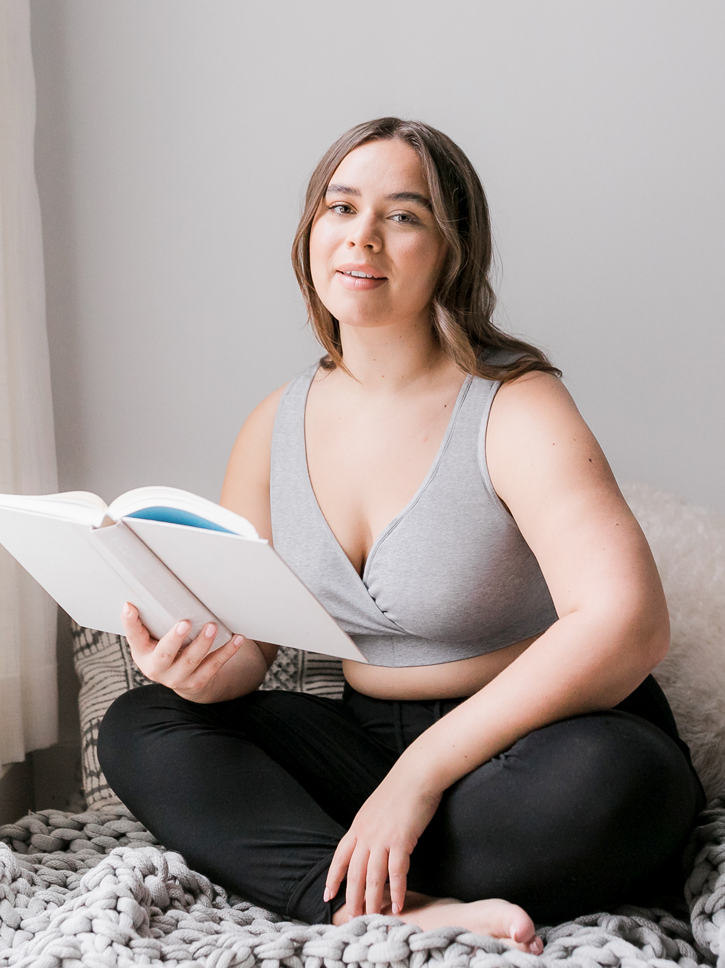 Model sitting and wearing the Organic Cotton Sleep & Nursing Bra in Grey Heather 