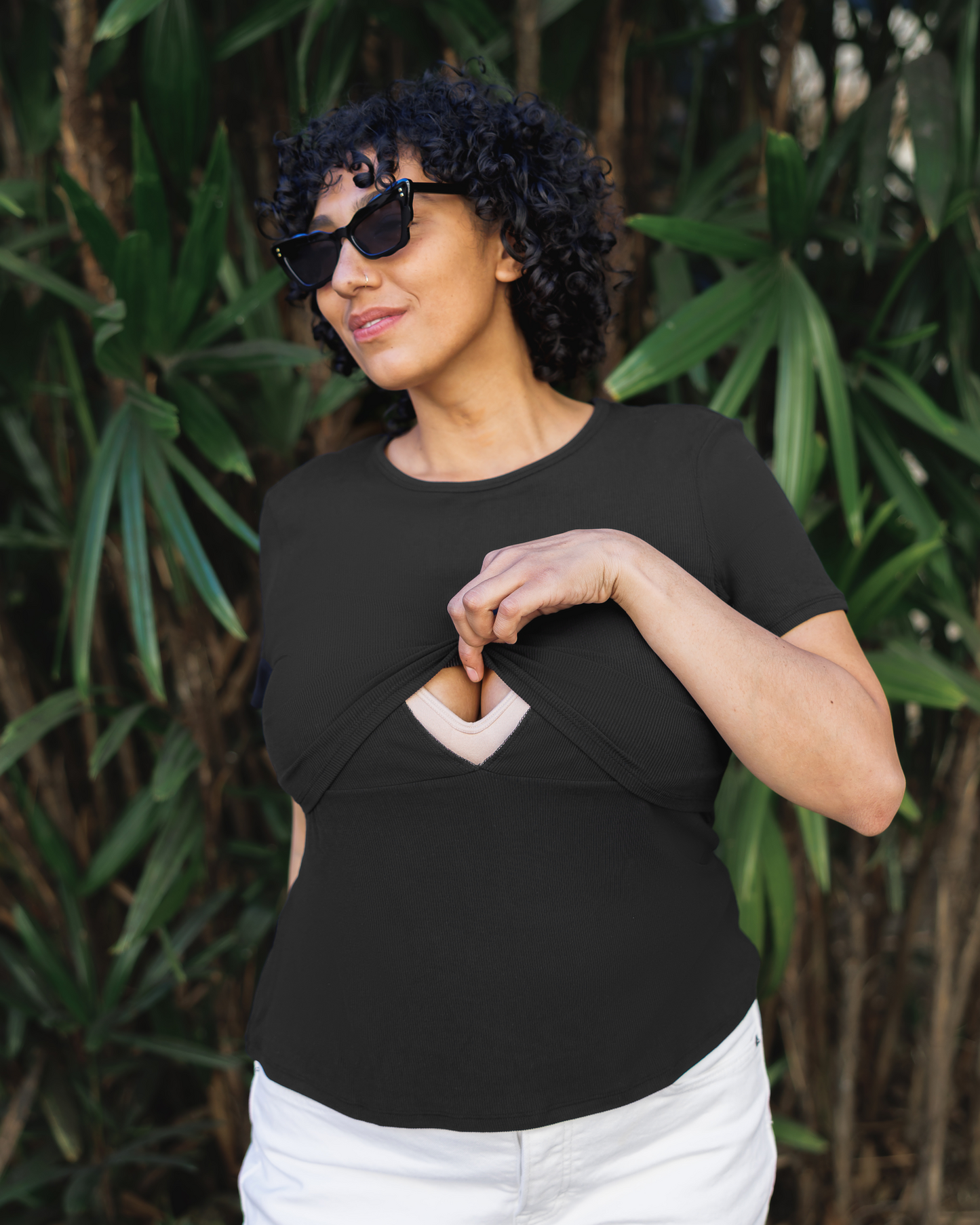 Model wearing Ribbed Bamboo Crew Neck Nursing T-shirt in Black, lifting up top outer layer to show nursing access