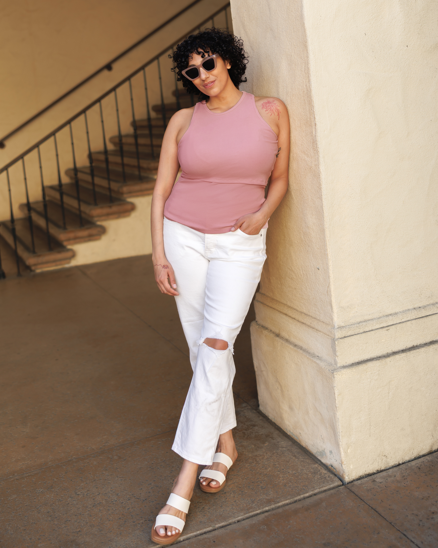 Model outside wearing the Ribbed Bamboo Racerback Nursing Tank in Light Mauve paired with cropped white jeans and sandals