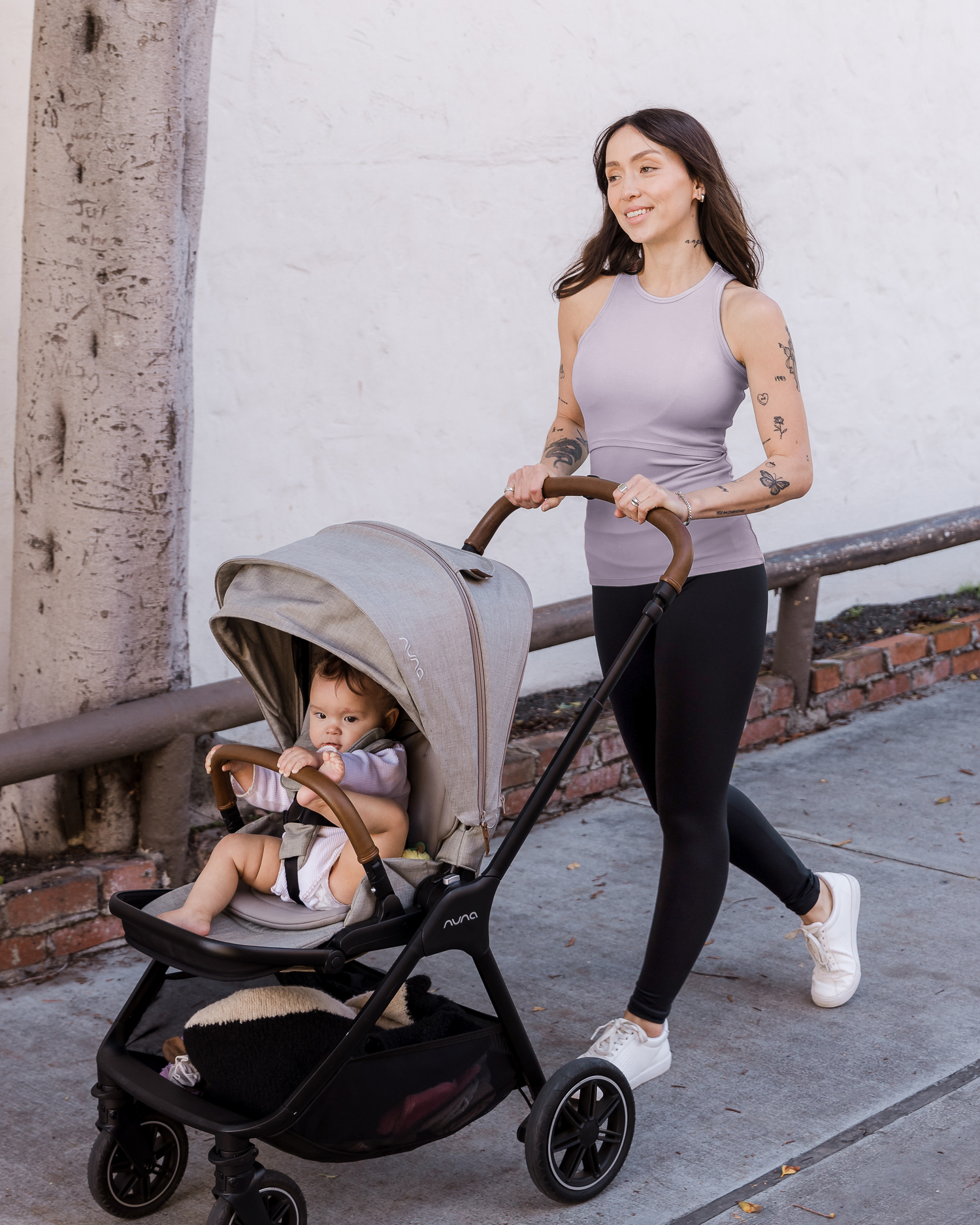 Model outside wearing the Ribbed Bamboo Racerback Nursing Tank in Lavender Mist paired with Louisa Legging and tennis shoes, and pushing baby in stroller