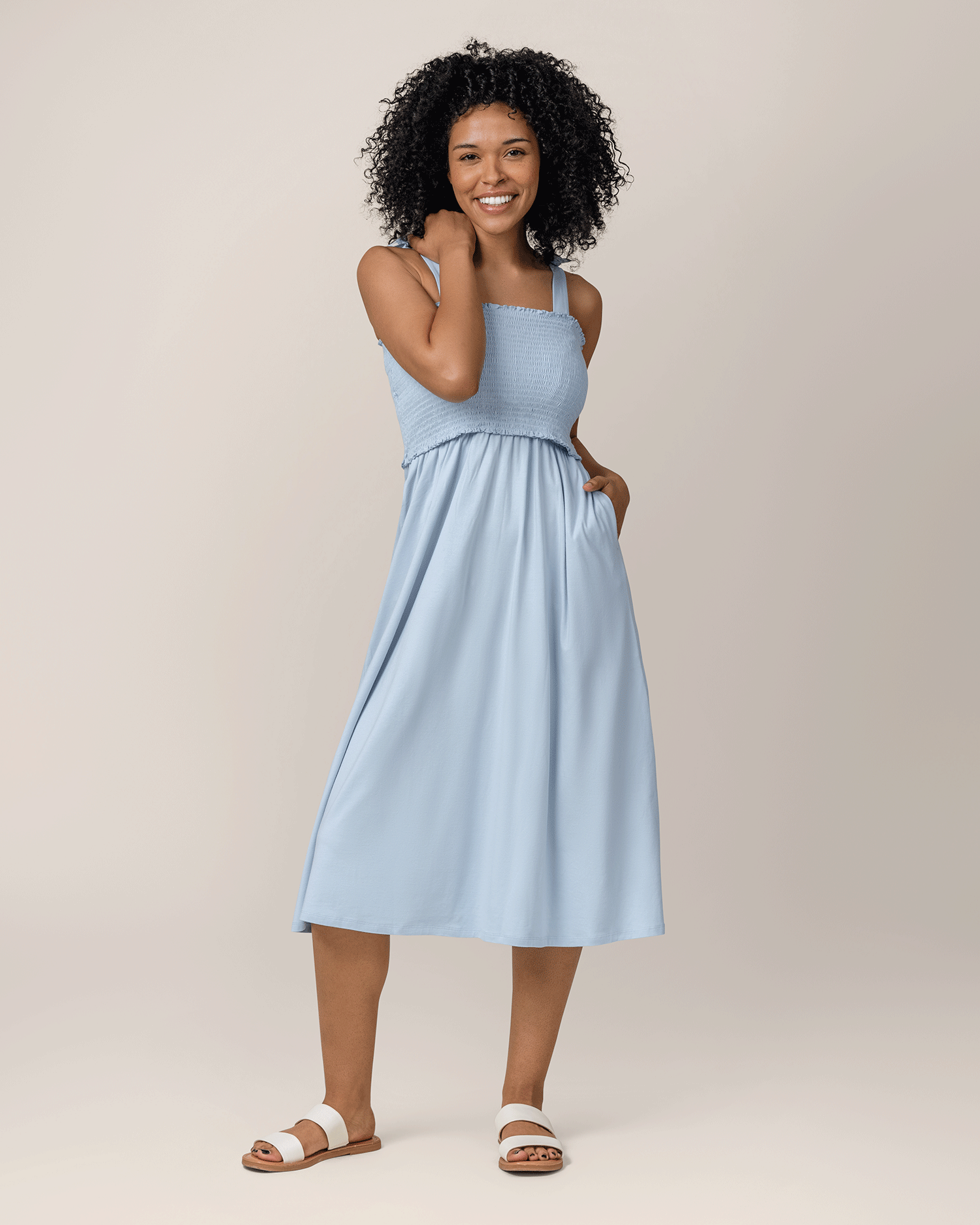 Front view of model wearing the Sienna Smocked Maternity & Nursing Dress in French Blue, with one hand in pocket@model_info:Marisa is 5'8" and wearing a Small.