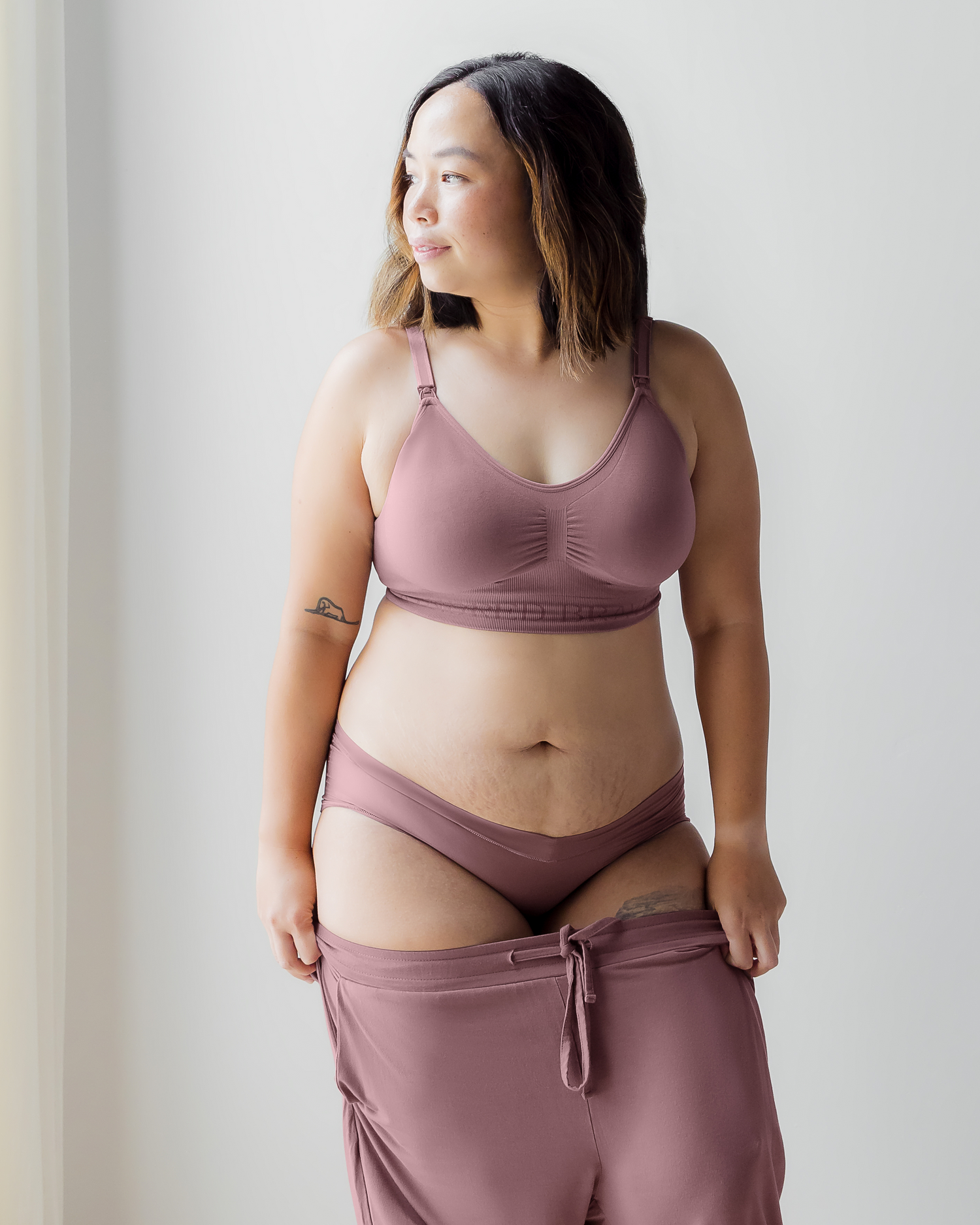 Model wearing the Simply Sublime Nursing bra in Twilight paired with matching Grow With Me Hipster and Everyday Lounge Jogger, pulling joggers up