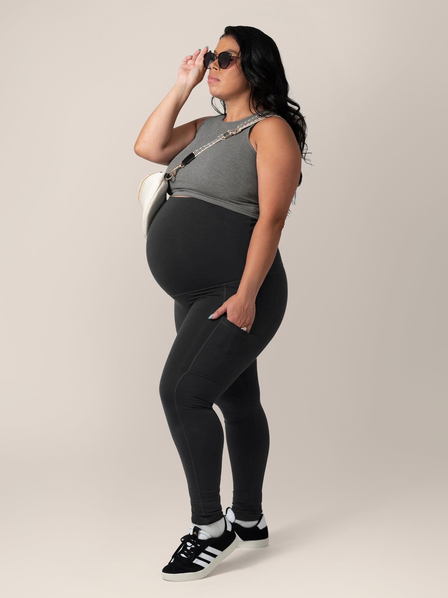 Full body side view of model wearing the Sublime® Bamboo Maternity & Nursing Longline Bra in Charcoal , paired with black Louisa legging, cross-bod bag and sungaksses.