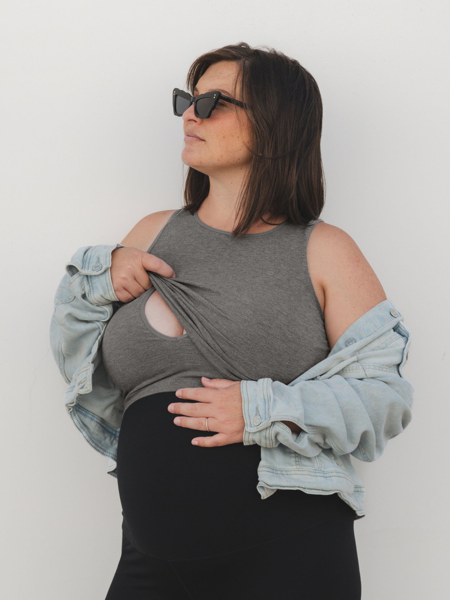 Full body view of model wearing the Sublime® Bamboo Maternity & Nursing Longline Bra in Charcoal, paired with an open slouched denim jacket @model_info:Shelby is wearing an X-Large.