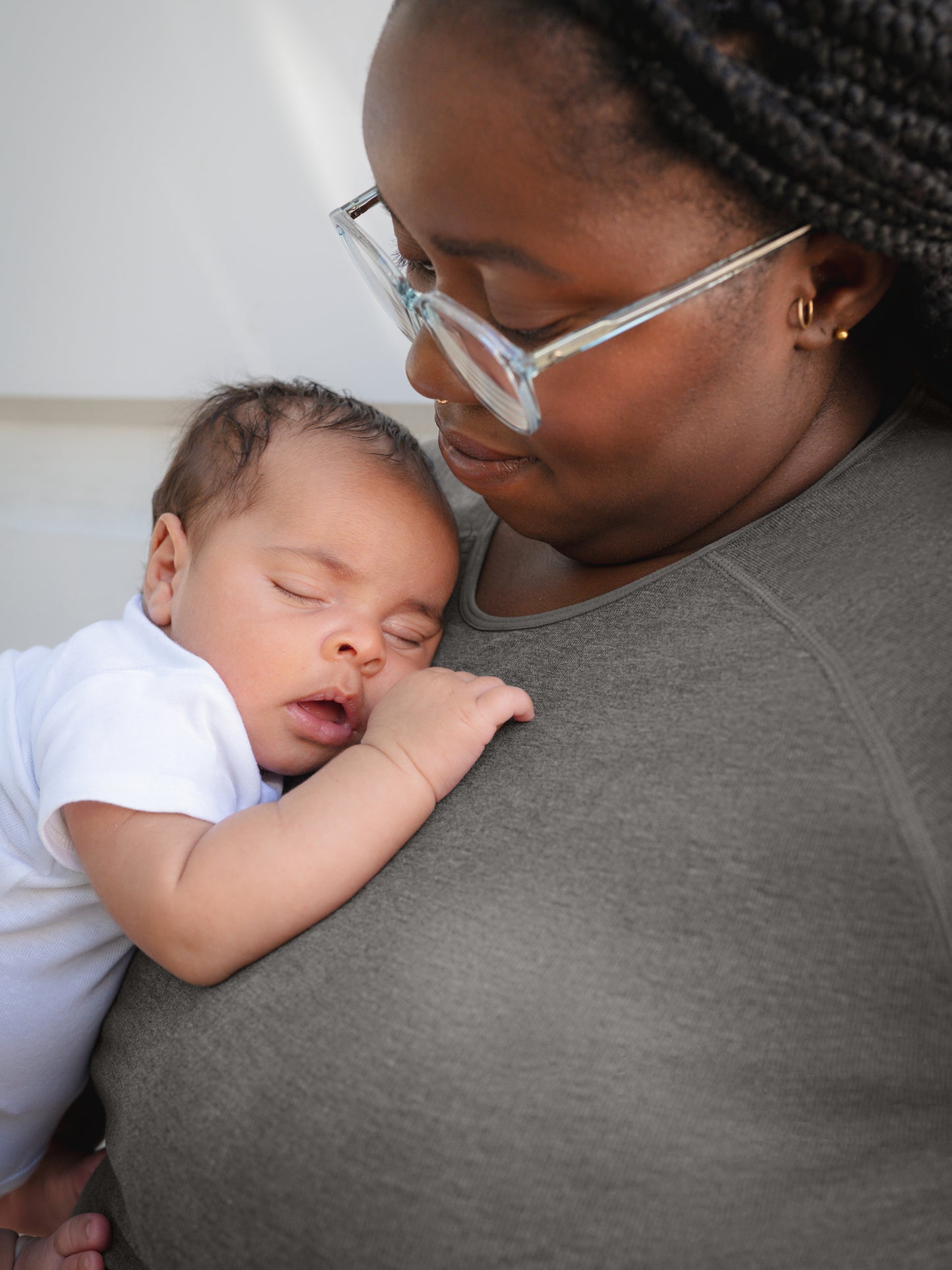 Close up of model wearing the Sublime® Bamboo Maternity & Nursing Cropped Long Sleeve Top in Charcoal, showing neckline and trim detail, and holding baby. 