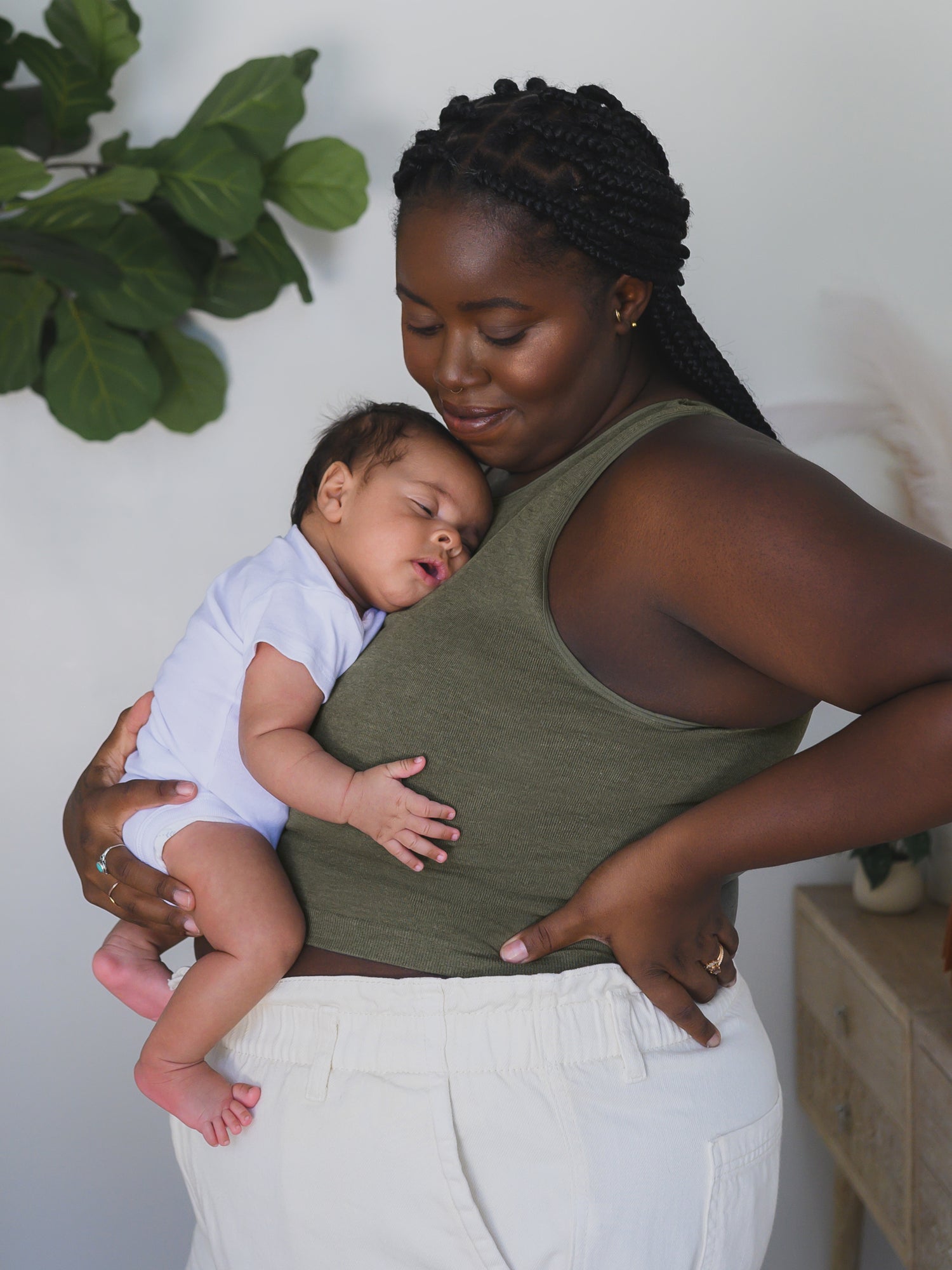 Side view of model wearing the Sublime® Bamboo Maternity & Nursing Longline Bra in Olive Heather. holding baby resting against her chest