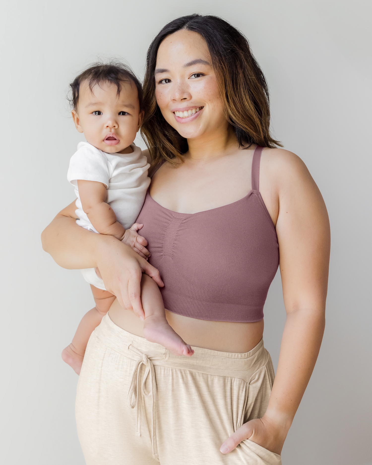 Model wearing the Sublime® Bamboo Hands-Free Pumping Lounge & Sleep Bra in Twilight, holding baby in one arm