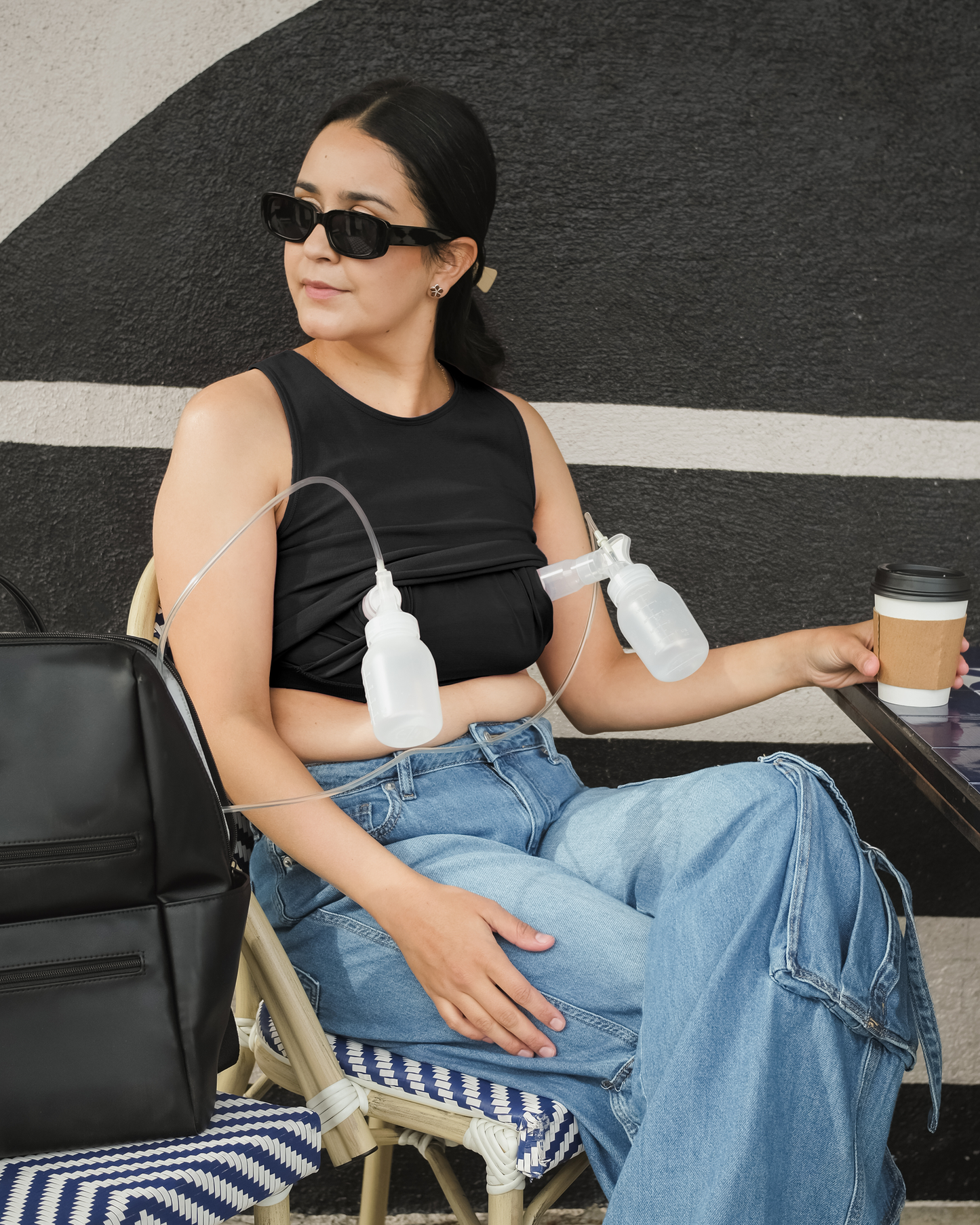 Model outside wearing and pumping in the Sublime® Bamboo Hands-Free Pumping Longline Bra Top in Black; paired with jeans @model_info:Dama is wearing a Medium Busty.