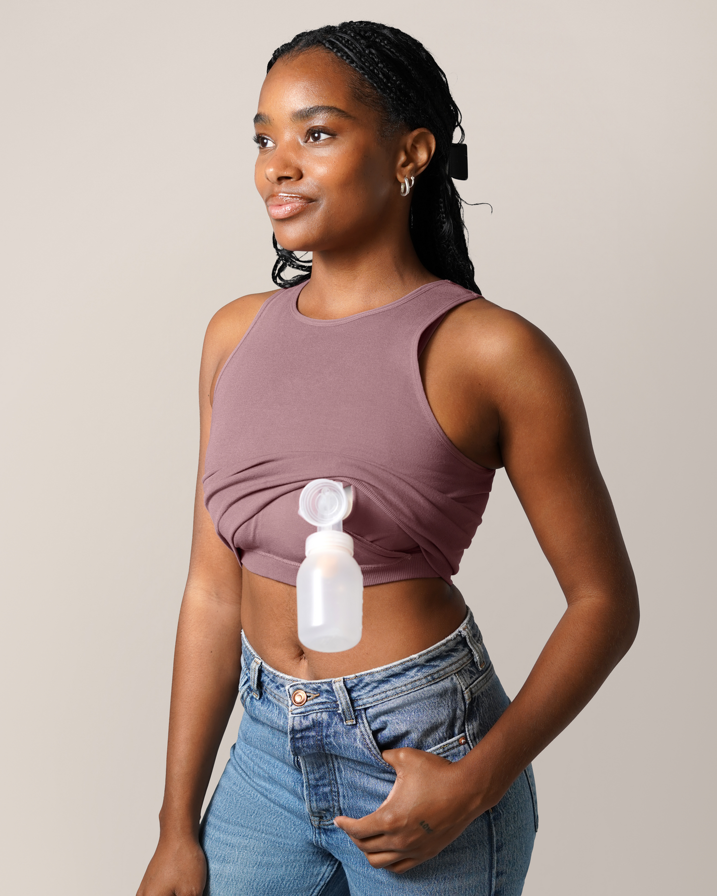 3/4 view of model wearing the Sublime® Bamboo Hands-Free Pumping Longline Bra Top in Twilight, showing pumping access with one pump fland and bottle inserted; paired with jeans