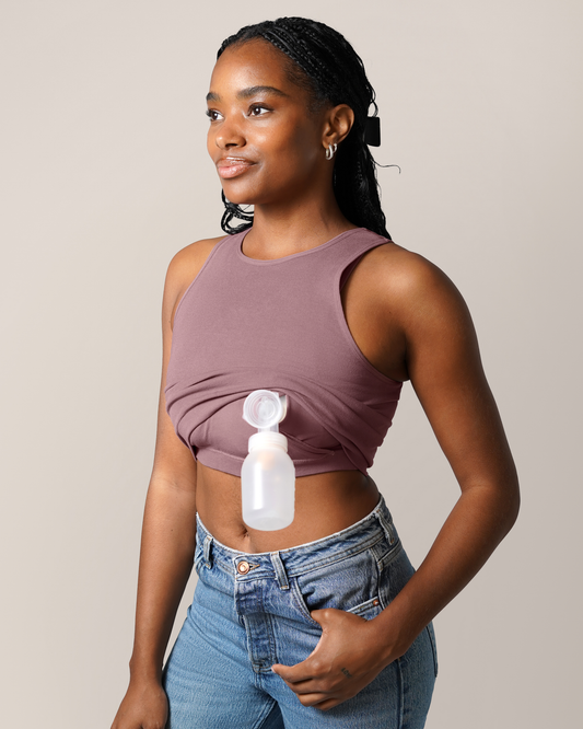 3/4 view of model wearing the Sublime® Bamboo Hands-Free Pumping Longline Bra Top in Twilight, showing pumping access with one pump fland and bottle inserted; paired with jeans @model_info:Josie is wearing a Small Busty.