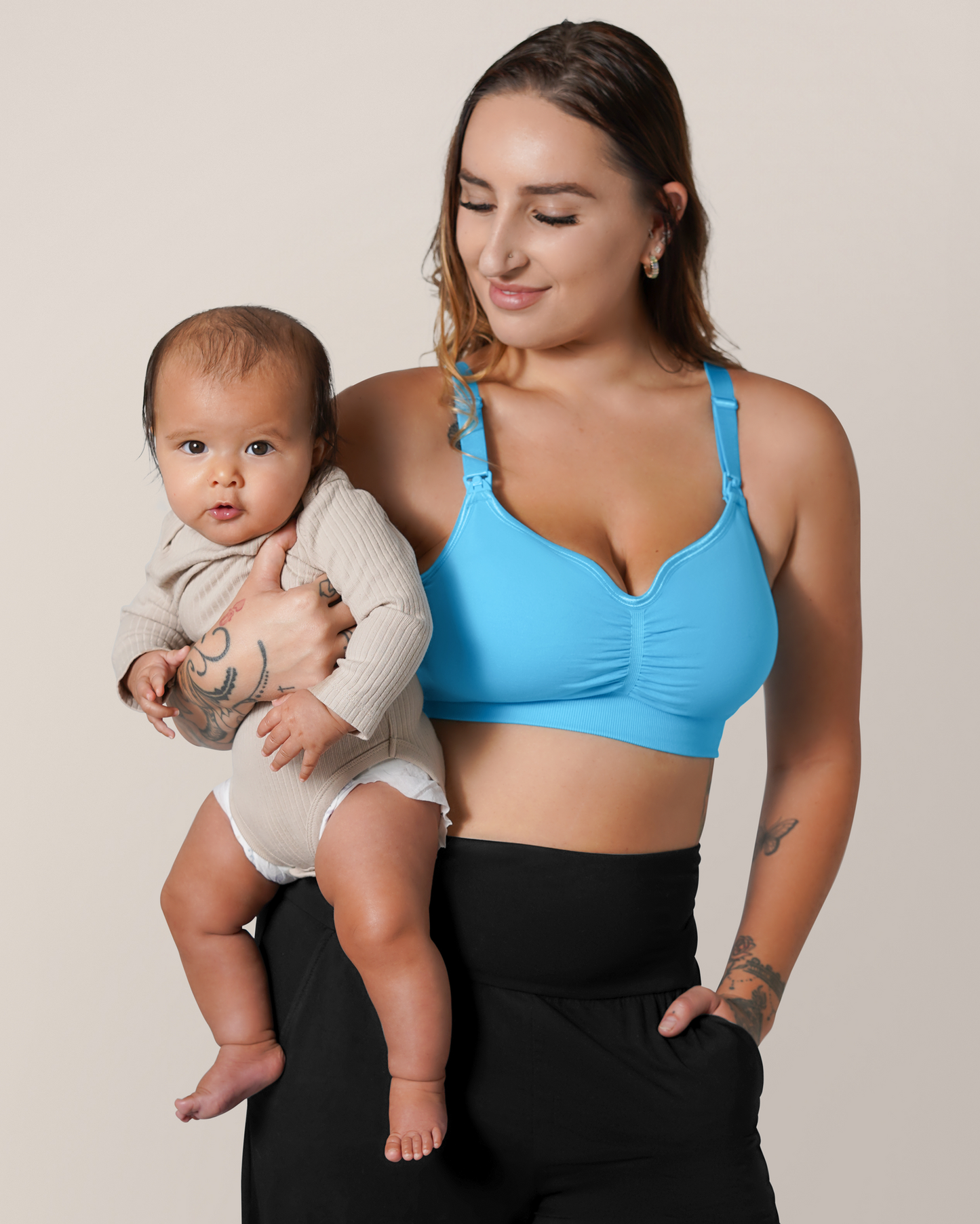 Front view of model wearing the Tatum Seamless Maternity & Nursing Bralette in Blue Lagoon, holding baby. @model_info:Anna is wearing a Small Busty.