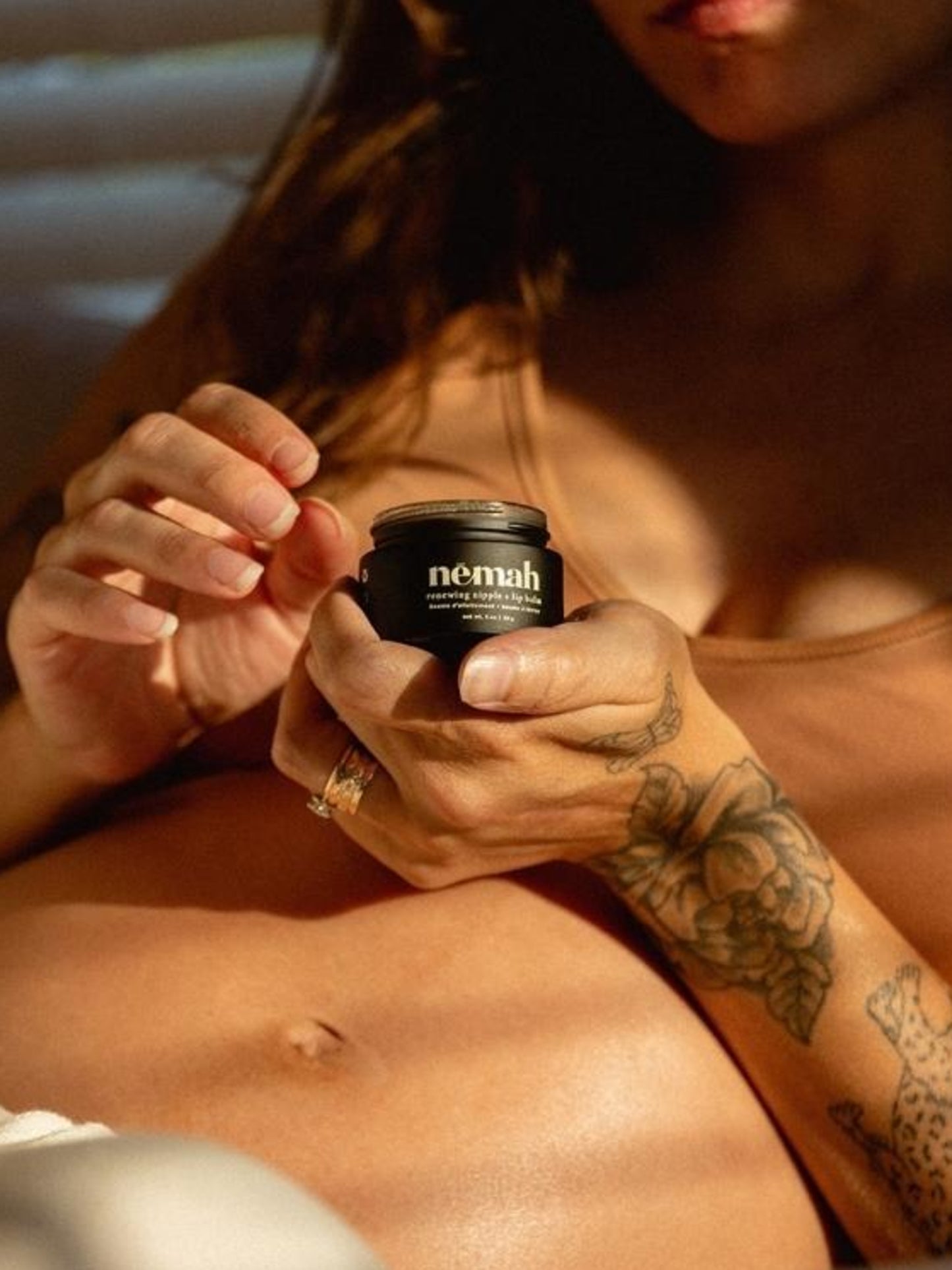 Model holding open container of Nēmah - Renewing Nipple + Lip Balm | Kindred Bravely